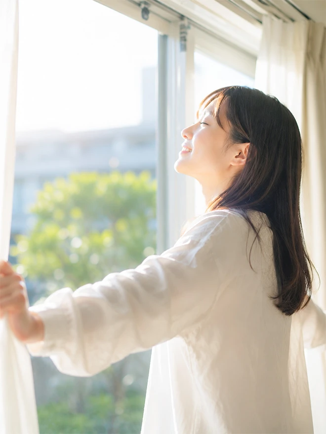 窓辺で朝日を浴びる女性